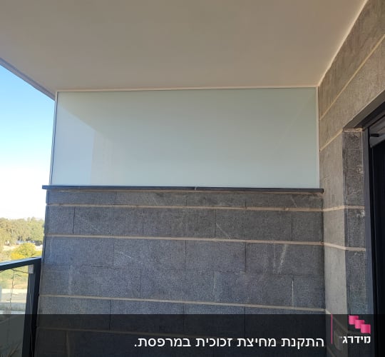 זכוכית שקופה מותקנת על קיר אבן במרפסת
